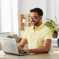 indian man with laptop working at home office